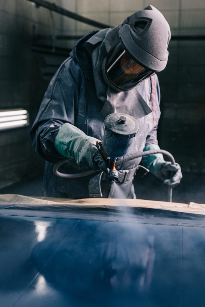 Spuiten van metaal met beschermende kleding in werkplaats van De Poel