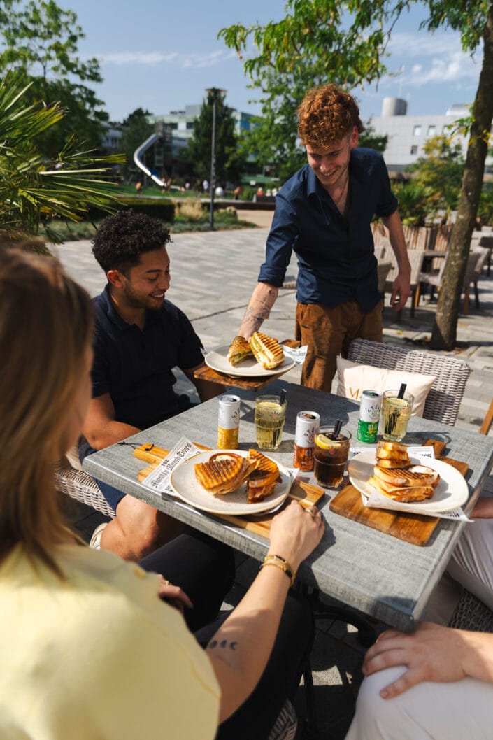 Medewerker serveert lunchgerecht op het terras van Tranquilo